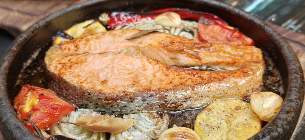 Premium Norwegian Butter Salmon cooked in a traditional stone oven with butter, roasted potatoes, garlic, tomatoes and peppers at Nasreddin Restaurant in Antalya